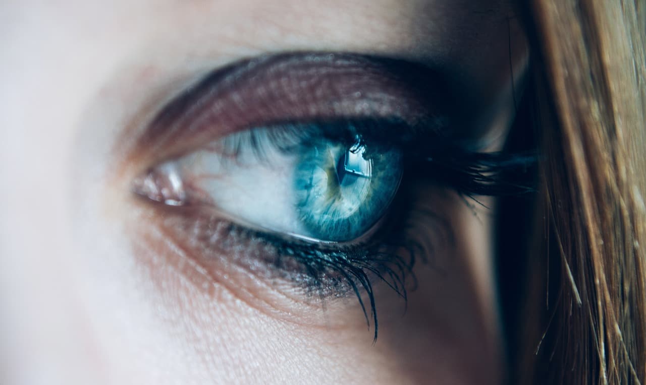 Dark, full lashes around a blue eye, seen from the side